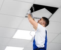 Elektricien installeert verlichting en bekabeling in een systeemplafond